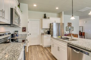 A modern kitchen with white cabinets, granite countertops, stainless steel appliances, and a dishwasher.