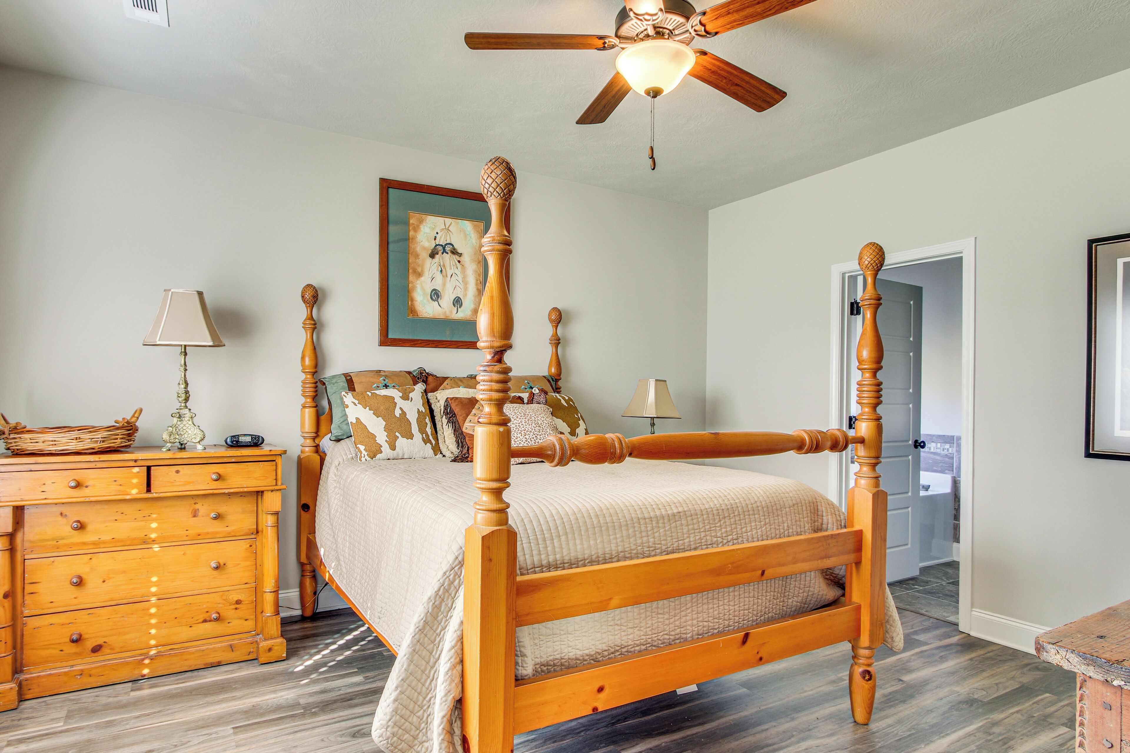 A four-poster bed with a wooden frame and a ceiling fan above.