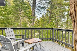 A wooden deck with two Adirondack chairs and a small table, surrounded by dense forest. - 2 Mi to Lake Arrowhead: Treetop Retreat w/ Deck (Lake Arrowhead)