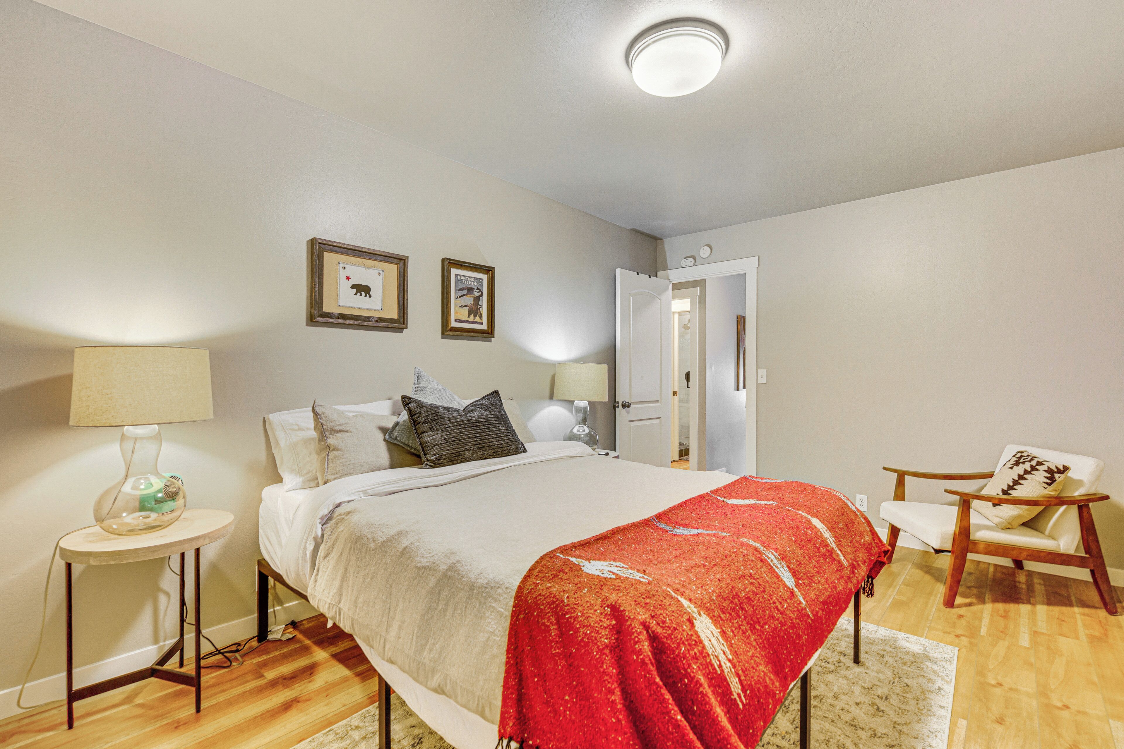A bedroom with a bed, bedside tables, a chair, and a door.