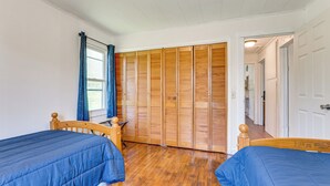 Ein Zimmer mit zwei hölzernen Betten, einem Holzschrank und einem Fenster mit Vorhängen.