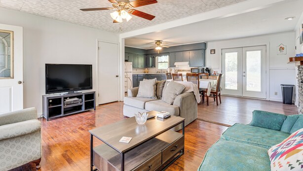 Ein geräumiges Wohnzimmer mit Flachbildfernseher, Couchtisch, Sofa und Deckenventilator.