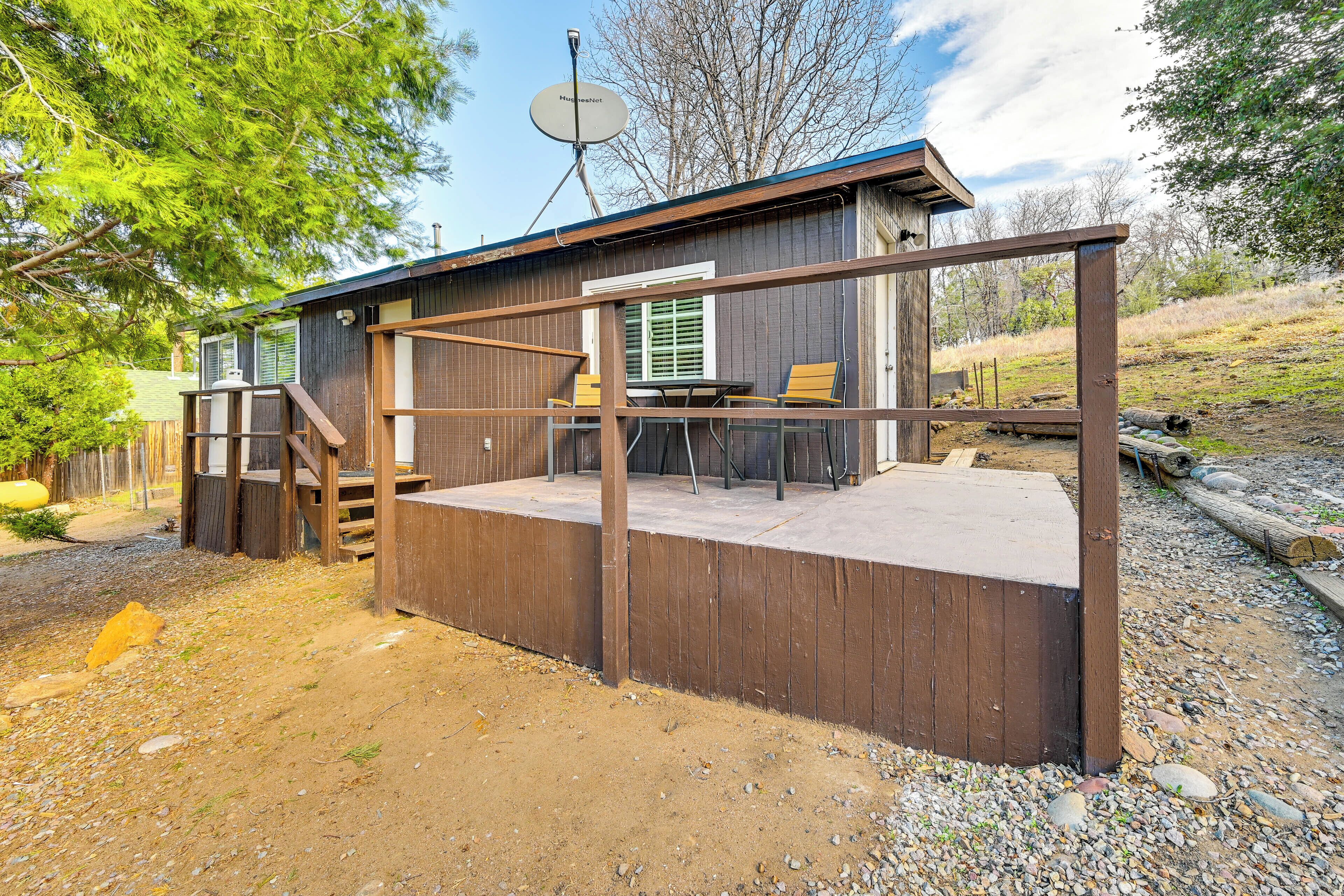A wooden deck with a metal railing, a satellite dish, and a table with chairs.