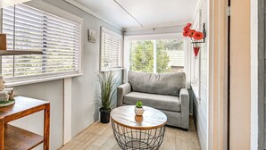 Un coin douillet avec un canapé gris, une table basse ronde en bois et une plante en pot.