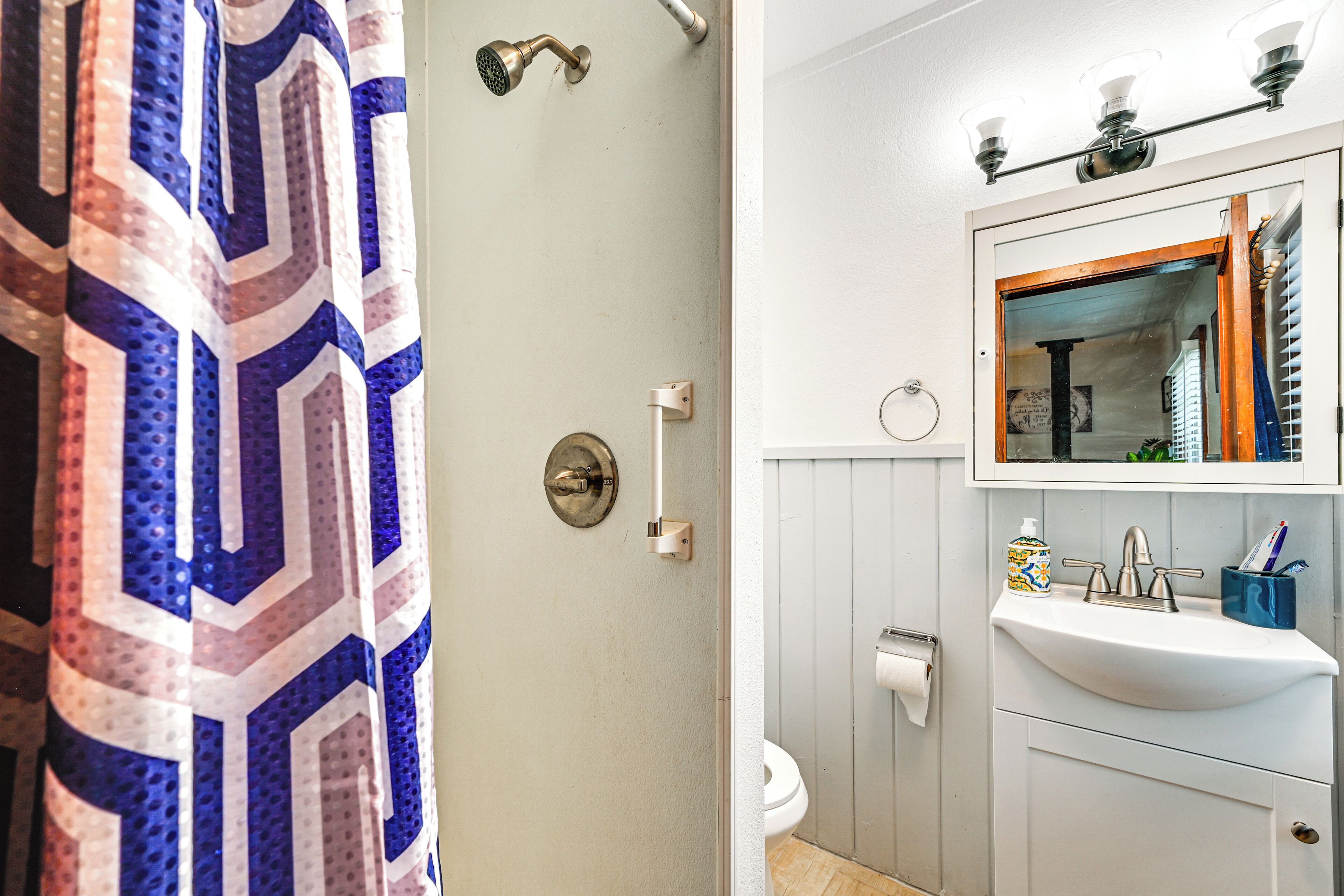 Un baño con cortina de ducha, inodoro, lavamanos y espejo.