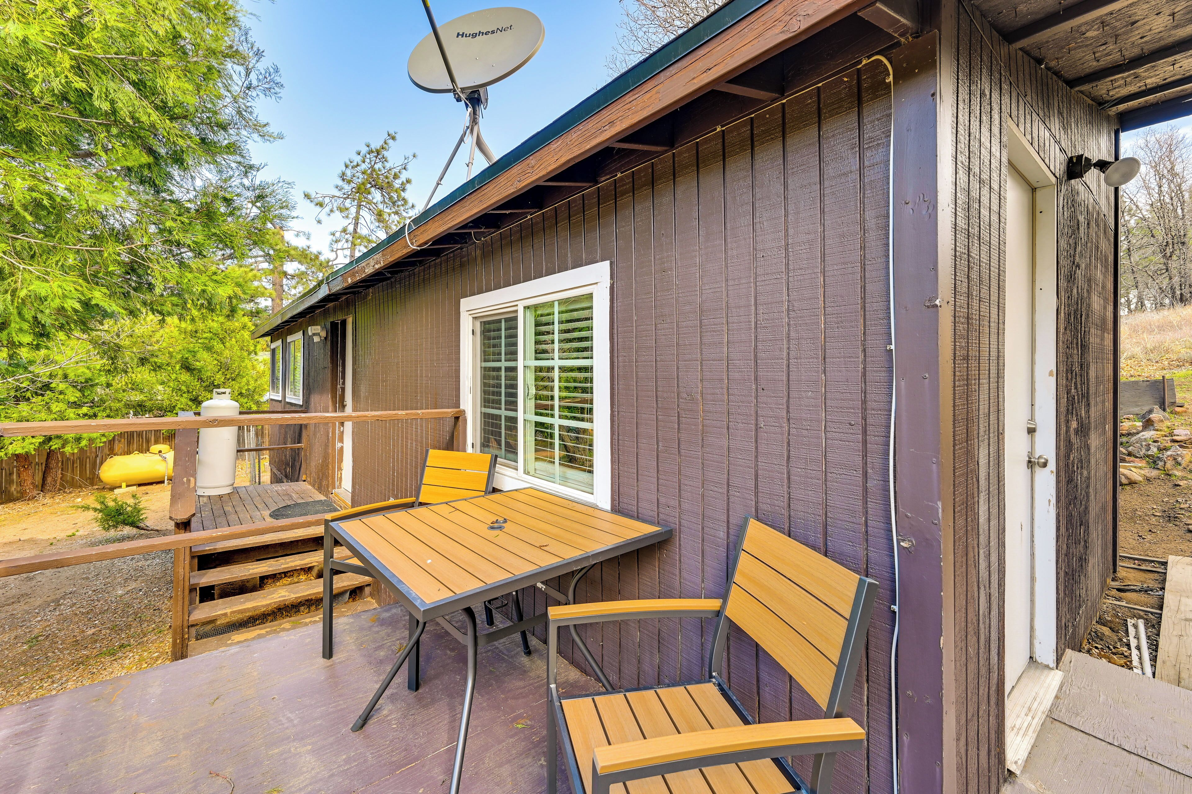 A wooden deck with a table and chairs, a satellite dish, and a door leading to a covered area.