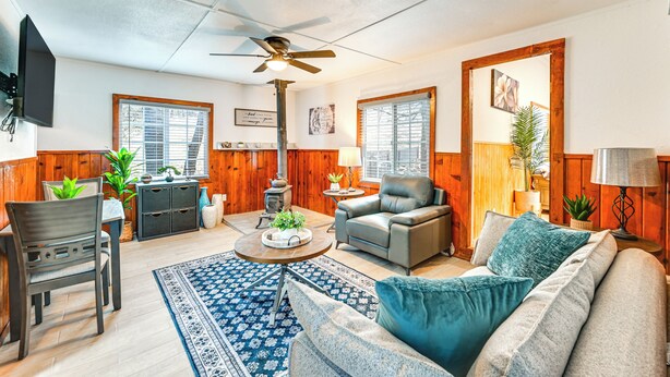Un salon chaleureux avec un canapé, un fauteuil et une table basse, des murs en bois et un ventilateur de plafond.