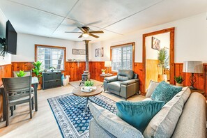 Ein gemütliches Wohnzimmer mit einer Couch, einem Sessel und einem Couchtisch, Holzwänden und einem Deckenventilator.