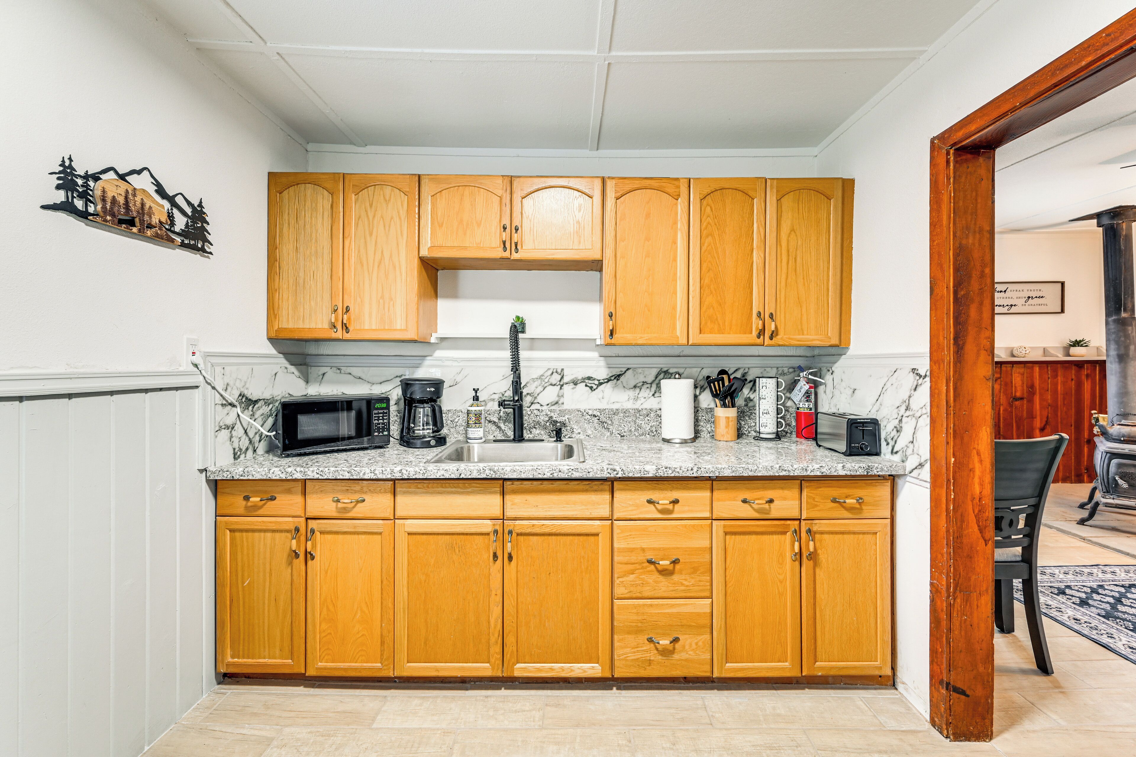A kitchen with wooden cabinets, a marble countertop, and a sink.