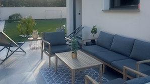 An outdoor seating area with a sofa, chairs, and a coffee table. There is a view of a garden and trees in the background. - Contemporary home in Vaison-la-Romaine  Comfort, light & heated pool in Provence (Vaison-la-Romaine)