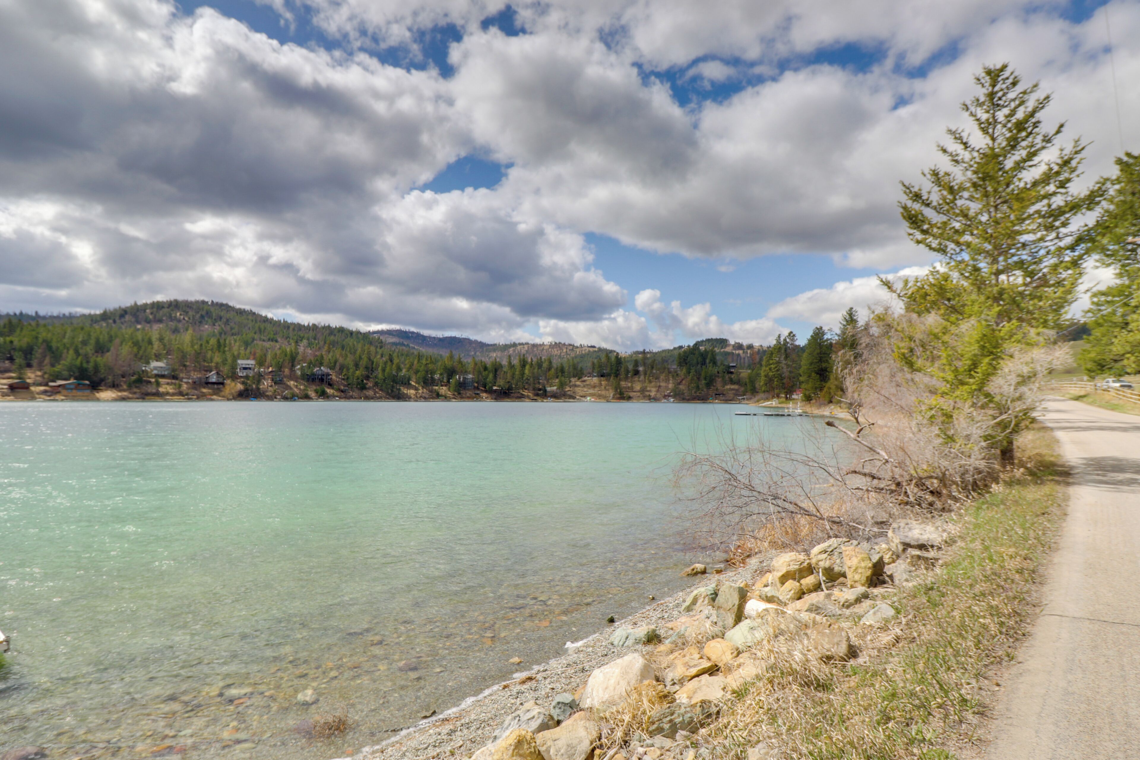 A clear lake with a rocky shoreline and a road running alongside.