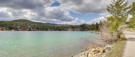 A clear lake with a rocky shoreline and a road running alongside.