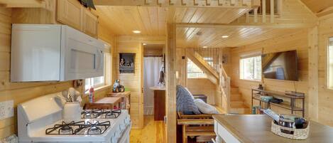 L’intérieur d’une cabane en bois comprend une cuisine, un coin repas et une chambre à coucher située en mezzanine.