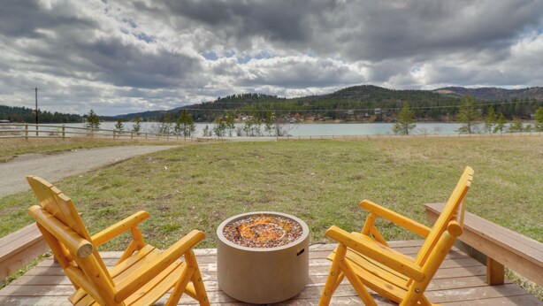 Terraza de madera con dos sillas amarillas y un pozo de fuego circular.