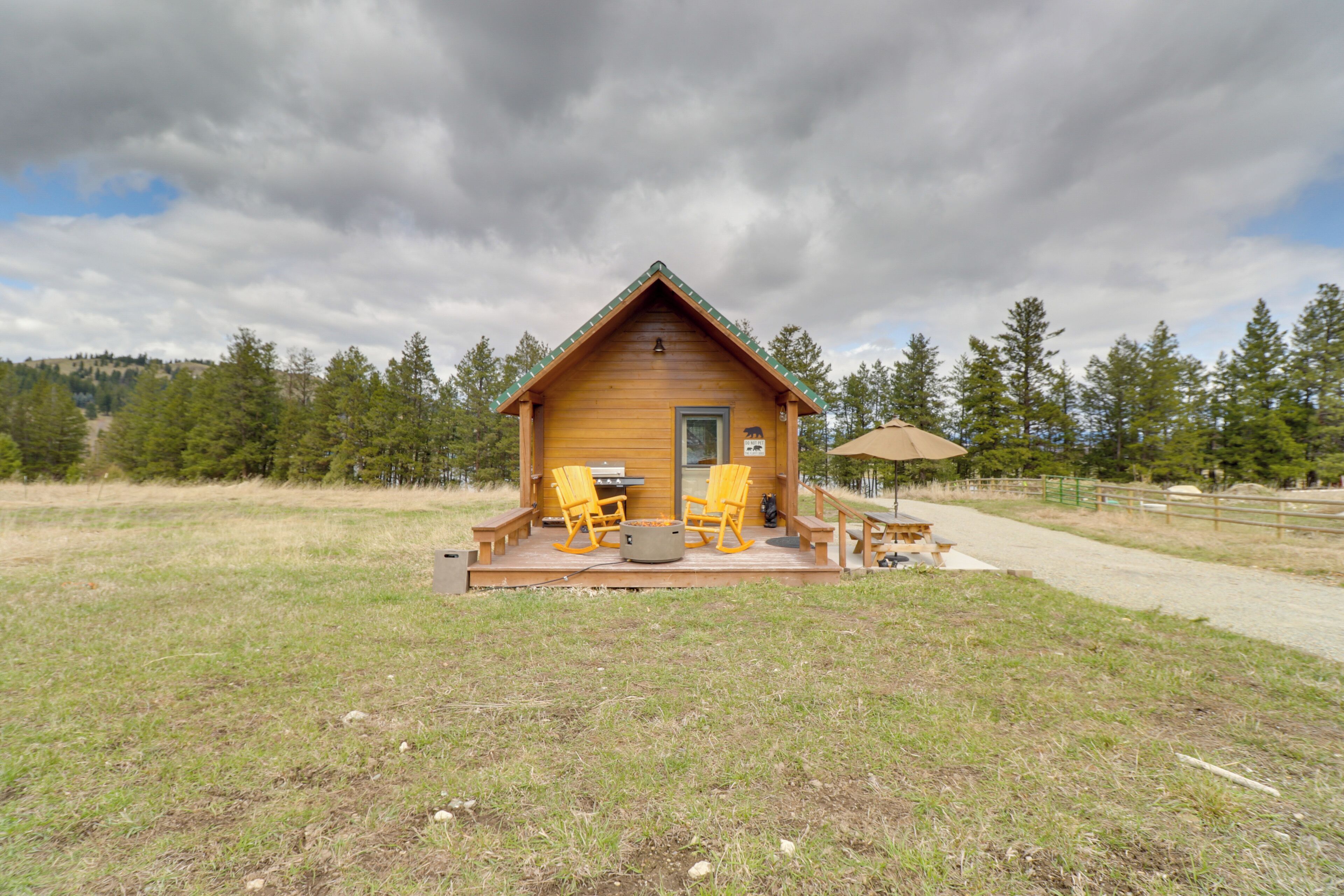 A wooden cabin with a porch, outdoor seating, and a fire pit.