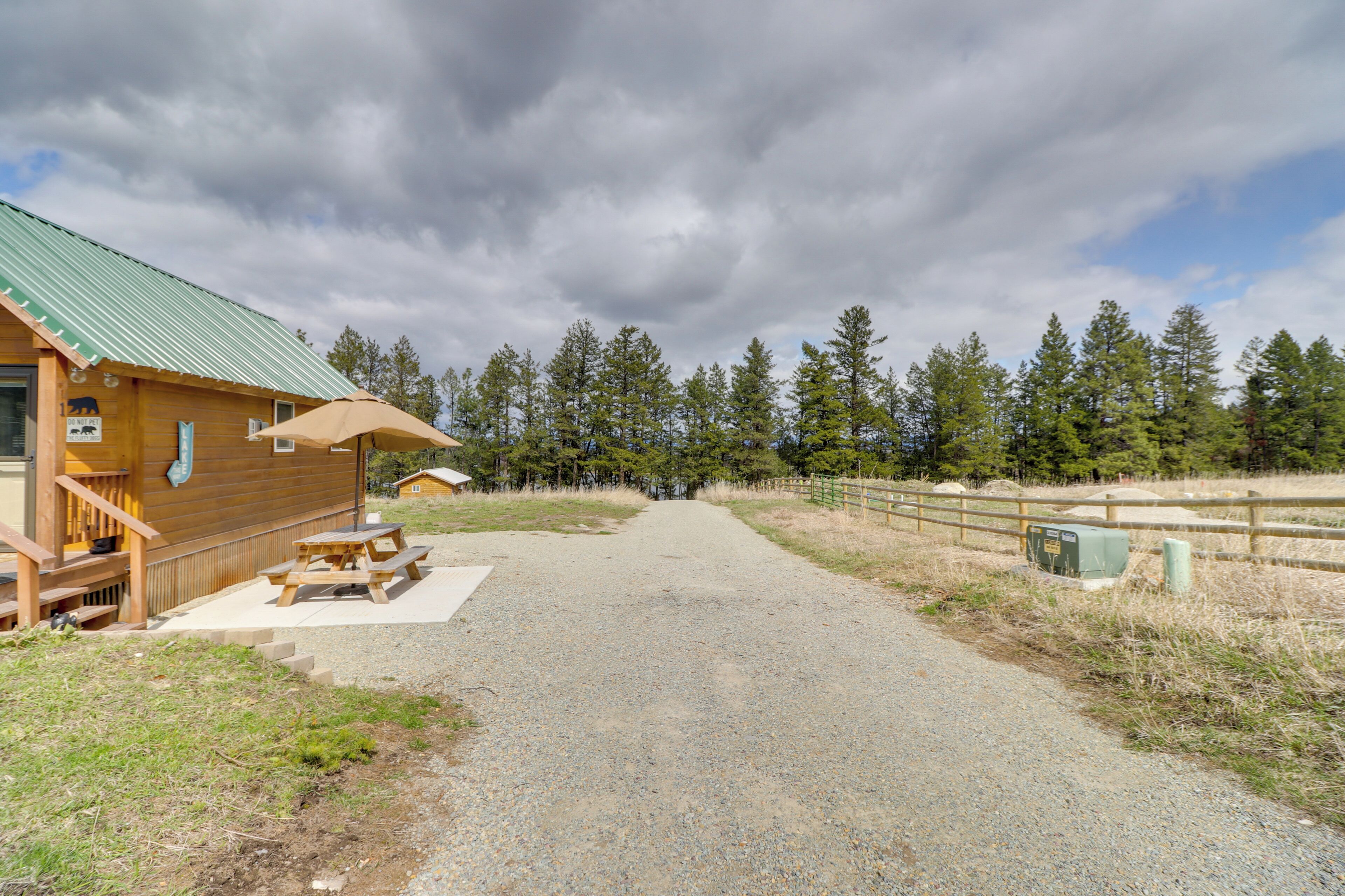 Une cabane en bois avec une allée de gravier menant à une table de pique-nique et à un espace abrité.