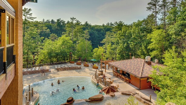 A pool area with a hot tub, lounge chairs, and a building with a tiled roof. - Chula Vista Condo: Resort Perks & Family Fun! (Wisconsin Dells)
