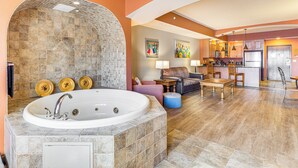 A spacious living area with a large stone-tiled jacuzzi, a cozy seating area with a sofa and armchairs, and a kitchen with wooden cabinets and pendant lighting. - Chula Vista Condo: Resort Perks & Family Fun! (Wisconsin Dells)