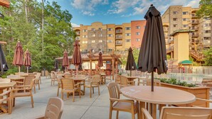 An outdoor patio area with multiple wooden tables and chairs, surrounded by umbrellas. - Chula Vista Condo: Resort Perks & Family Fun! (Wisconsin Dells)