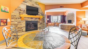 A modern living room with a stone fireplace, a round table, and metal chairs. - Chula Vista Condo: Resort Perks & Family Fun! (Wisconsin Dells)