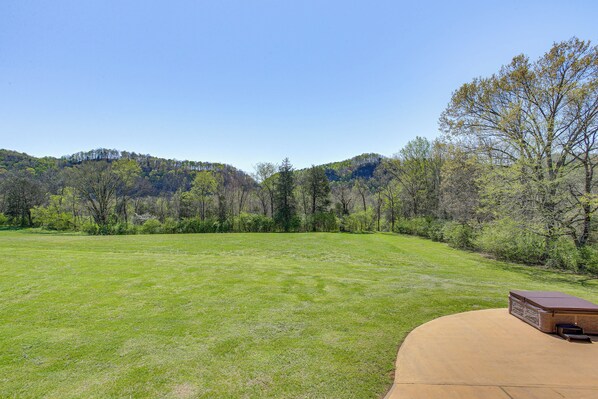 A large grassy field with a wooden deck and a hot tub. - Spacious Group Getaway Near Cumberland River! (Celina)
