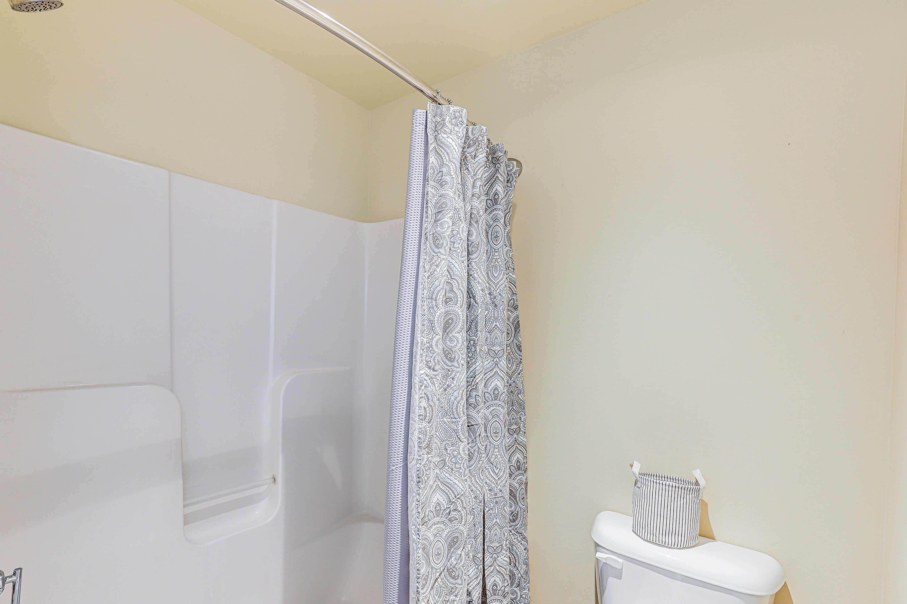 A bathroom with a shower curtain, a toilet, and a bathtub.