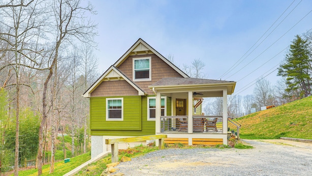A two-story house with a porch, a gravel driveway, and a stone wall. - On Farm: Charming Hendersonville Retreat! (Hendersonville)