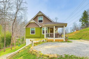 A two-story house with a porch, a gravel driveway, and a stone wall. - On Farm: Charming Hendersonville Retreat! (Hendersonville)