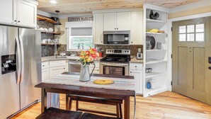 A kitchen with white cabinets, stainless steel appliances, a wooden table, and a sign that reads "FARMER'S MARKET". - On Farm: Charming Hendersonville Retreat! (Hendersonville)