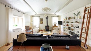 Ett mysigt vardagsrum med en svart soffa, ett träbord, en lampa, en bokhylla och en öppen spis.