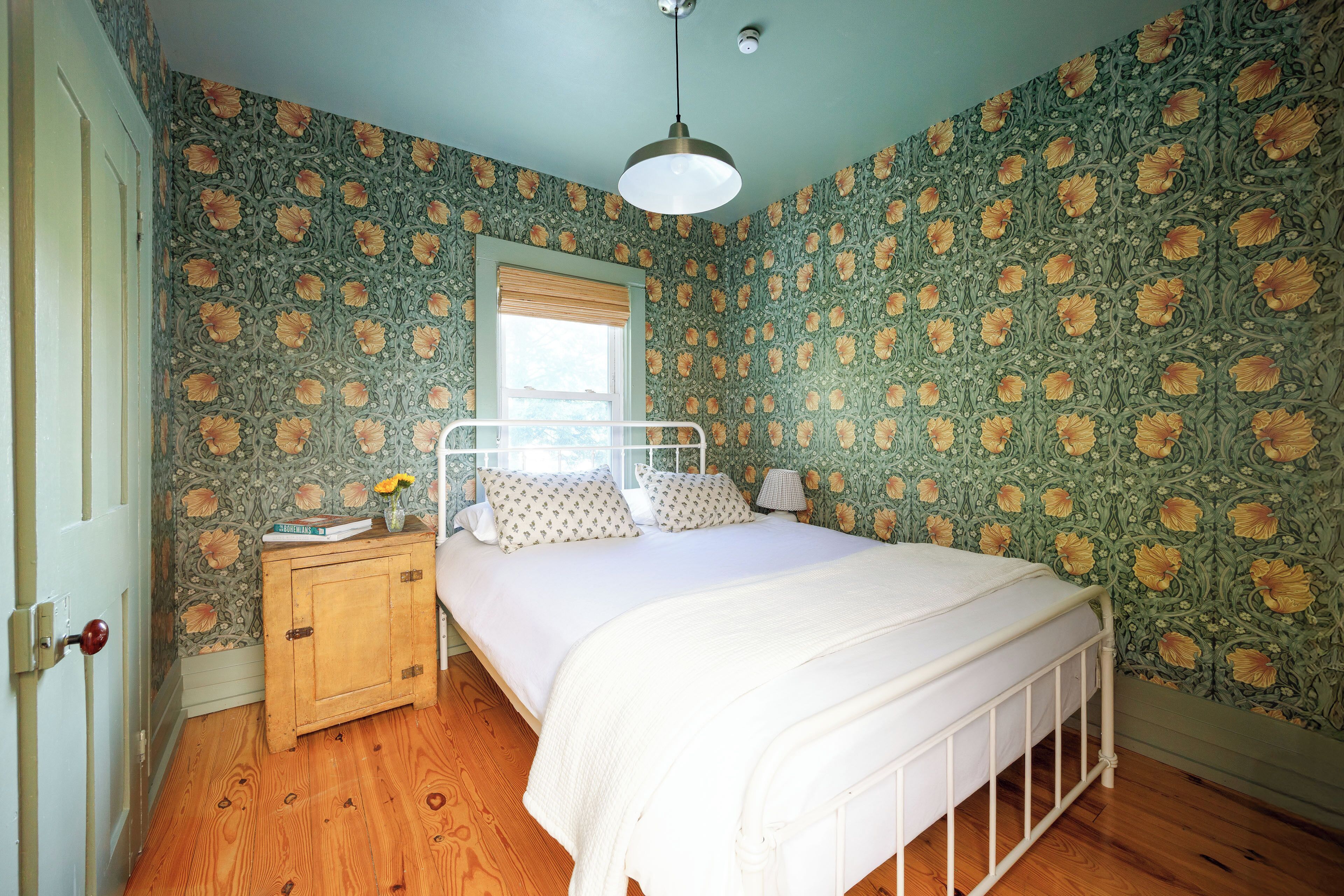 A bedroom with a bed, wooden nightstand, and a window with a blind.