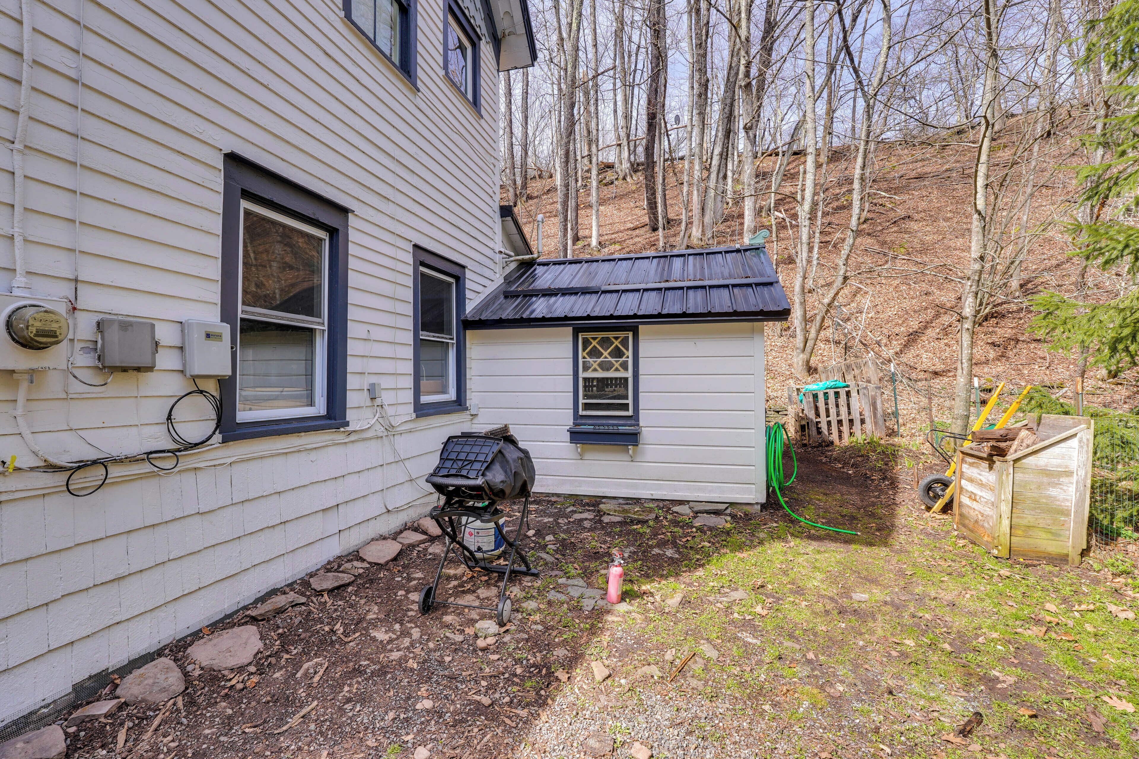 Ein Haus mit Garage, Schuppen und einem Garten mit Gartenschlauch.