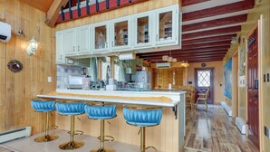 Eine Küche mit Holzwänden, einer weißen Arbeitsplatte und einer Bar mit blauen Barhocker.