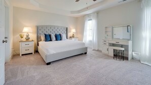 A bedroom with a large bed, bedside tables, a desk, a chair, a ceiling fan, and a window with curtains. - Patio & Grill: Modern Family Home in Hampstead (Hampstead)