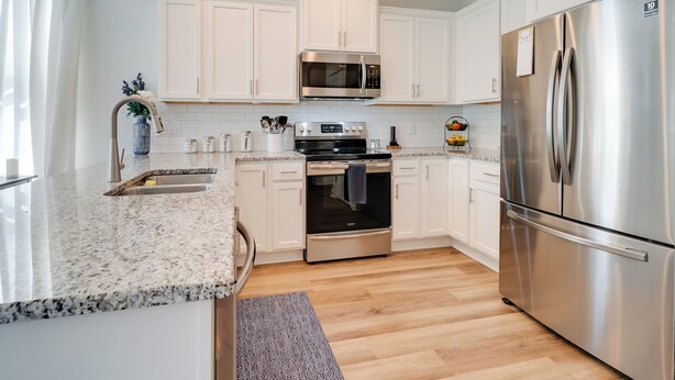A modern kitchen with white cabinets, stainless steel appliances, and a granite countertop. - Patio & Grill: Modern Family Home in Hampstead (Hampstead)
