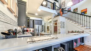 A modern kitchen with a central island, built-in appliances, and a staircase leading to an upper level. - Steps to Historic Riverfront: Chic Dtwn Condo! (Paducah)