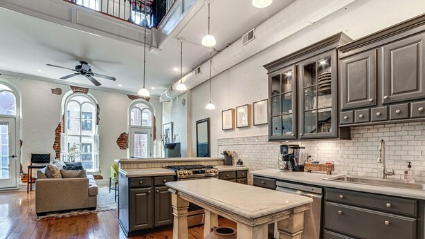 A spacious kitchen with dark cabinets, a large island, and a dining area with a table. - Steps to Historic Riverfront: Chic Dtwn Condo! (Paducah)