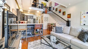 Un espacio habitable amplio con un sofá, una mesa de centro y una escalera que conduce a un nivel superior.