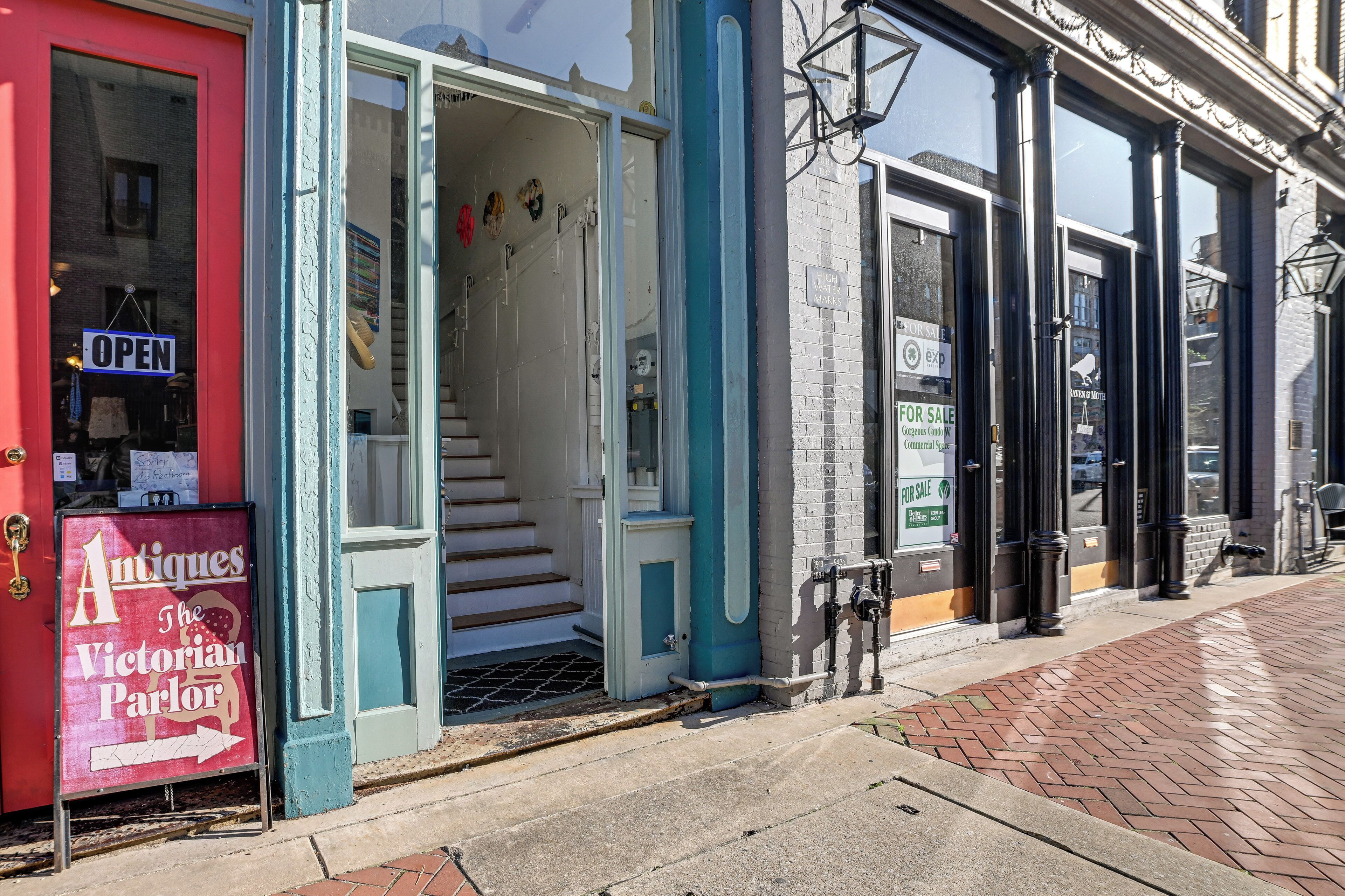 A storefront with a sign for 'Antiques The Victorian Parlor' and a 'For Sale' sign on the adjacent building.