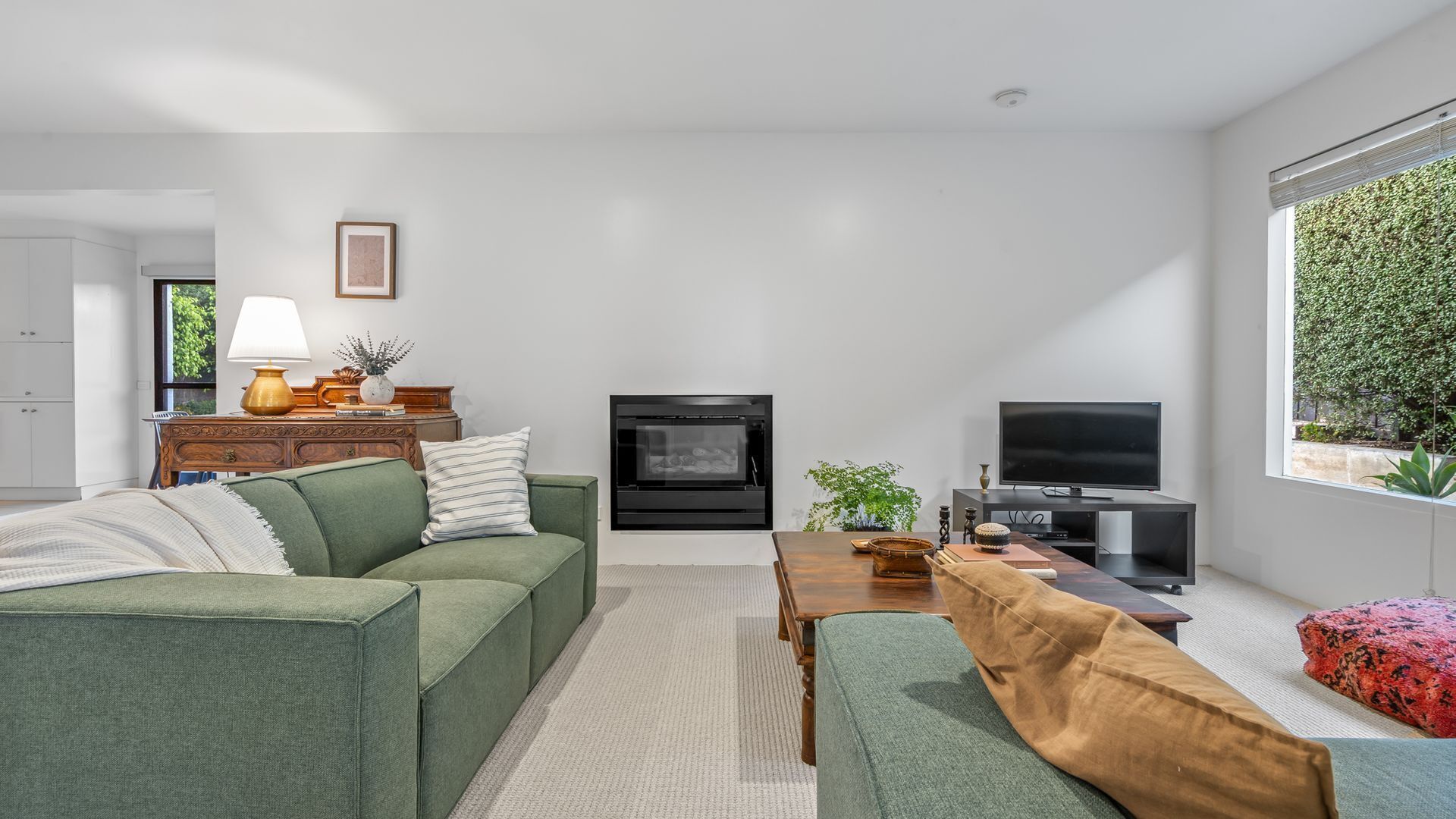 Una sala de estar moderna con un sofá, una mesa de centro, una chimenea y un televisor.