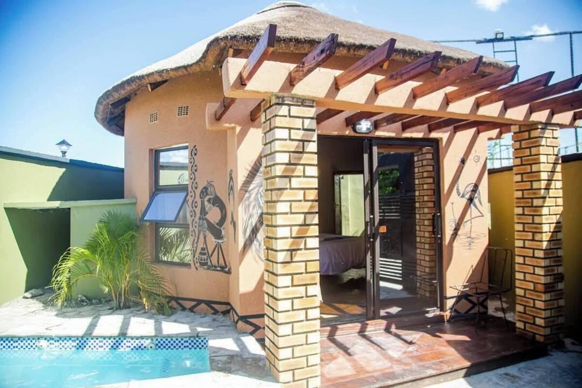 A building with a thatched roof, brick walls, and a pool area.