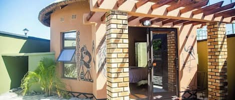 Un edificio con techo de paja, paredes de ladrillo y zona de piscina.