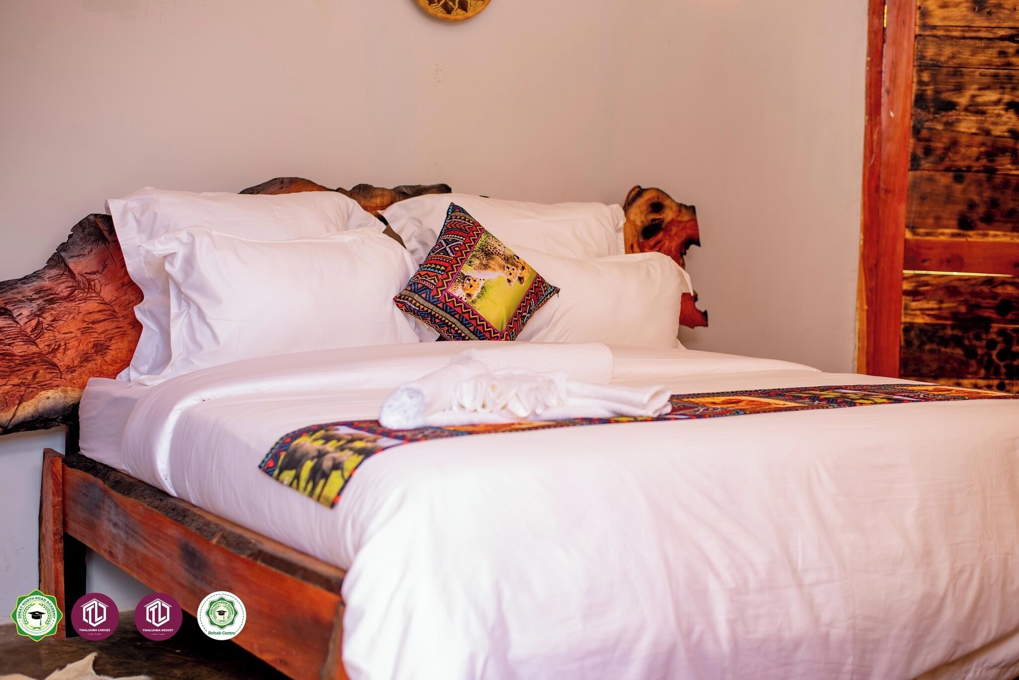 A neatly made bed with white linens and a colorful throw blanket.