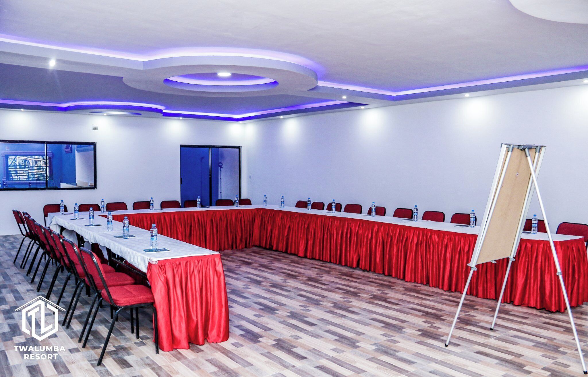 A conference room with a long table, red chairs, and a whiteboard.