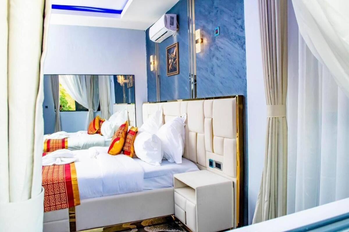 A bedroom with a large bed, a bedside table, and a window with curtains.