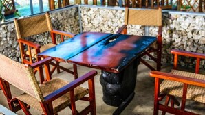 A wooden table with chairs around it, set against a stone wall. - Twalumba Resort & Hotel (Lusaka)