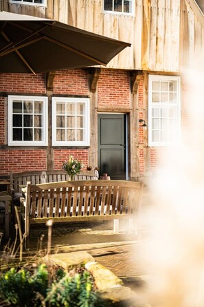 A wooden building with a brick facade, a bench, and a door.