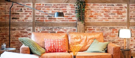 A cozy living room with a brick wall, leather sofa, and wooden coffee table.