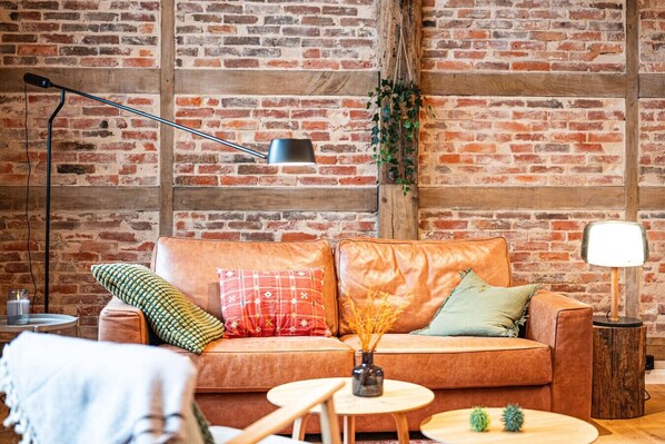 A cozy living room with a brick wall, leather sofa, and wooden coffee table.
