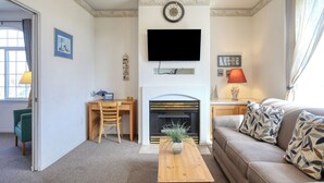 Una sala de estar con chimenea, televisor, sofá y un comedor con sillas y mesa.